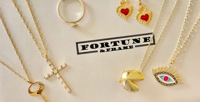 Key of F Necklace, Cross Pendant, Blush Fortune Cookie Ring, Sacred Heart Earrings, Gold Fortune Cookie Locket, and Evil Eye Locket on a Fortune & Frame Jewelry Box